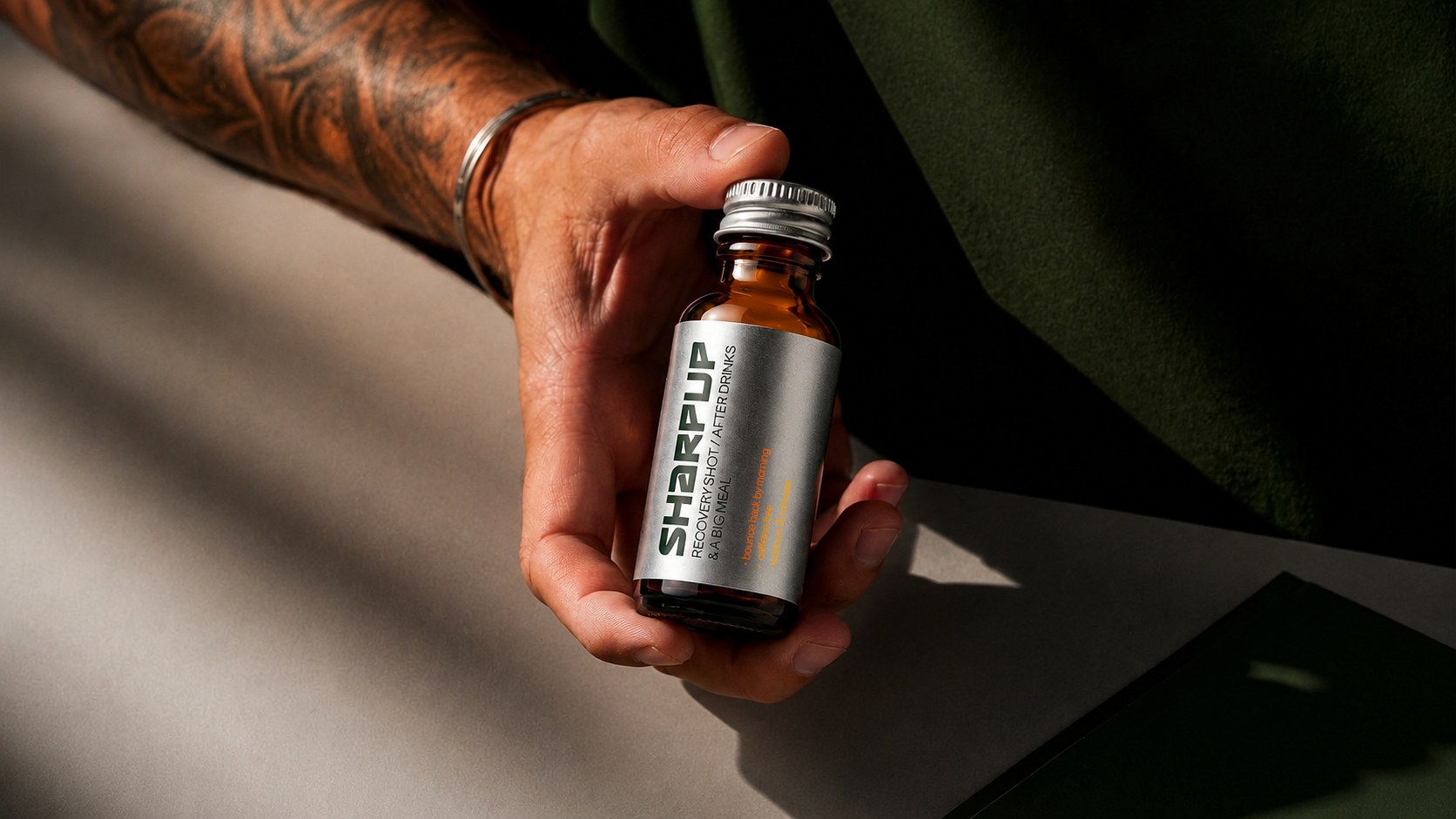 Hand holding a SharpUp recovery shot bottle in warm sunlight